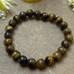Close-up of a Tiger Eye Reiki healing bracelet showcasing its unique golden-brown hue and chatoyancy pattern, symbolizing strength and protection.