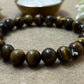  A collection of loose Tiger Eye stones placed on a white background, showcasing the stone's unique chatoyant pattern and natural warmth.
